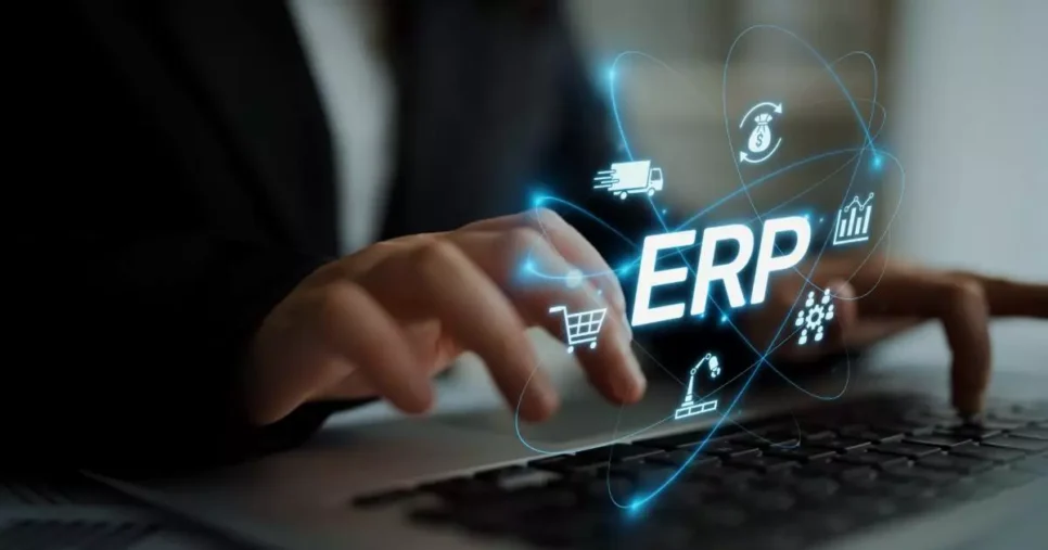 Pessoa digitando em um laptop, com a palavra “ERP” em destaque sobreposta à imagem, cercada por ícones digitais que representam logística, finanças, compras, produção e gestão de dados. Representação do uso de sistemas ERP na administração empresarial.