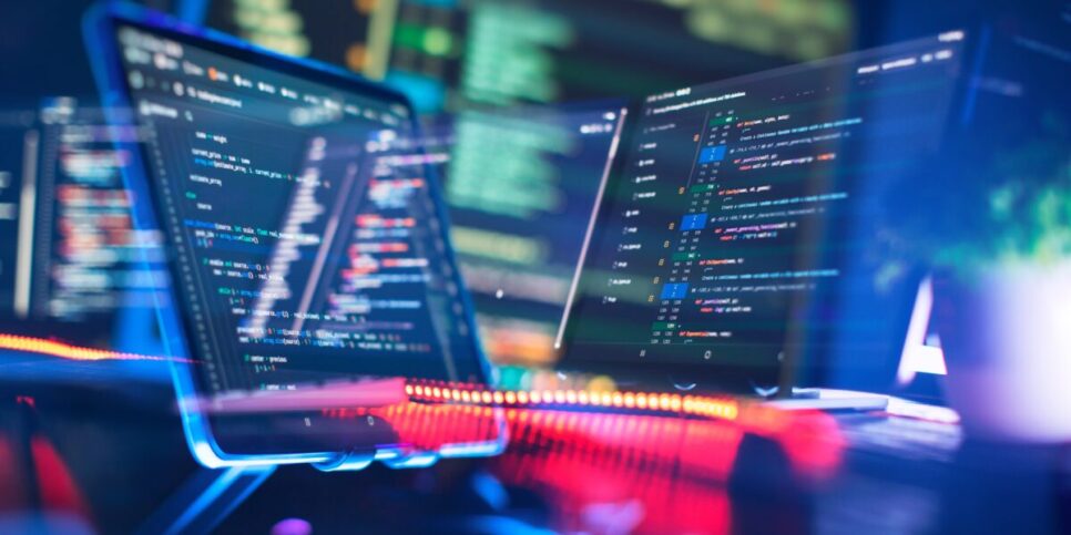 Imagem de telas de computadores com códigos de programação, representando o trabalho de desenvolvedores e profissionais de tecnologia (prompt, profissionais)