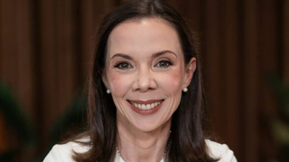 Mulher sorridente em close, de cabelos lisos e castanhos, usando brincos de pérola e roupa clara. A legenda informa que é Cintia Scovine Barcelos, do Bradesco.