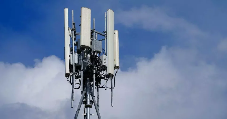Imagem de uma torre de telecomunicações com múltiplas antenas retangulares, provavelmente utilizadas para transmissão de sinal 4G, instalada sobre uma estrutura metálica contra um céu azul com algumas nuvens ao fundo, antena, 4g, vivo KPMG