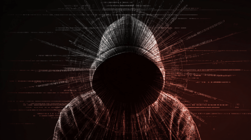 Hacker anônimo em ambiente escuro com telas abstratas, simbolizando ameaça cibernética que preocupa empresas indianas.