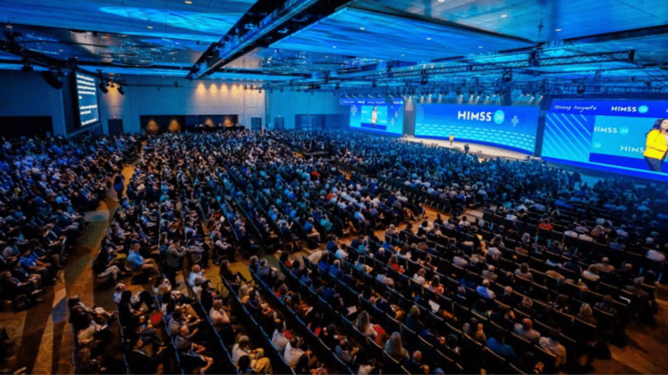 Auditório lotado na HIMSS durante conferência sobre tecnologia, saúde digital e cibersegurança no setor de healthcare.