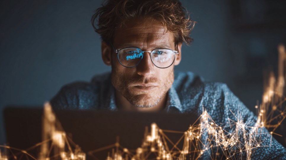 Homem com óculos analisando gráficos financeiros e dados digitais no laptop, ilustrando o impacto da inteligência artificial no mercado.